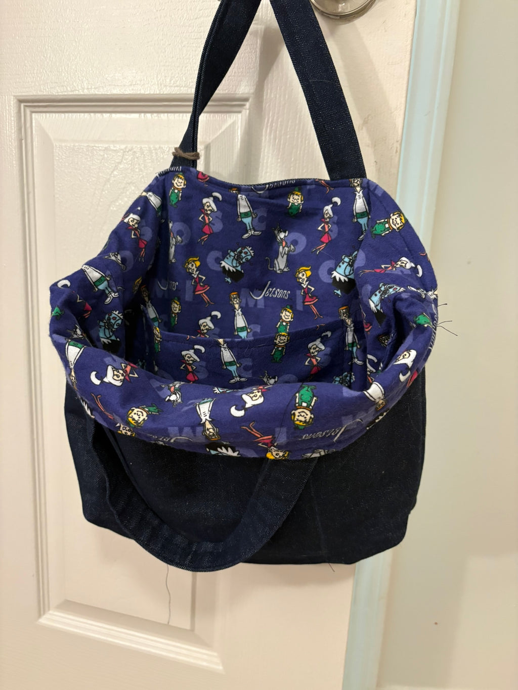 Open small denim tote showing colorful Jetsons fleece lining and interior pocket.