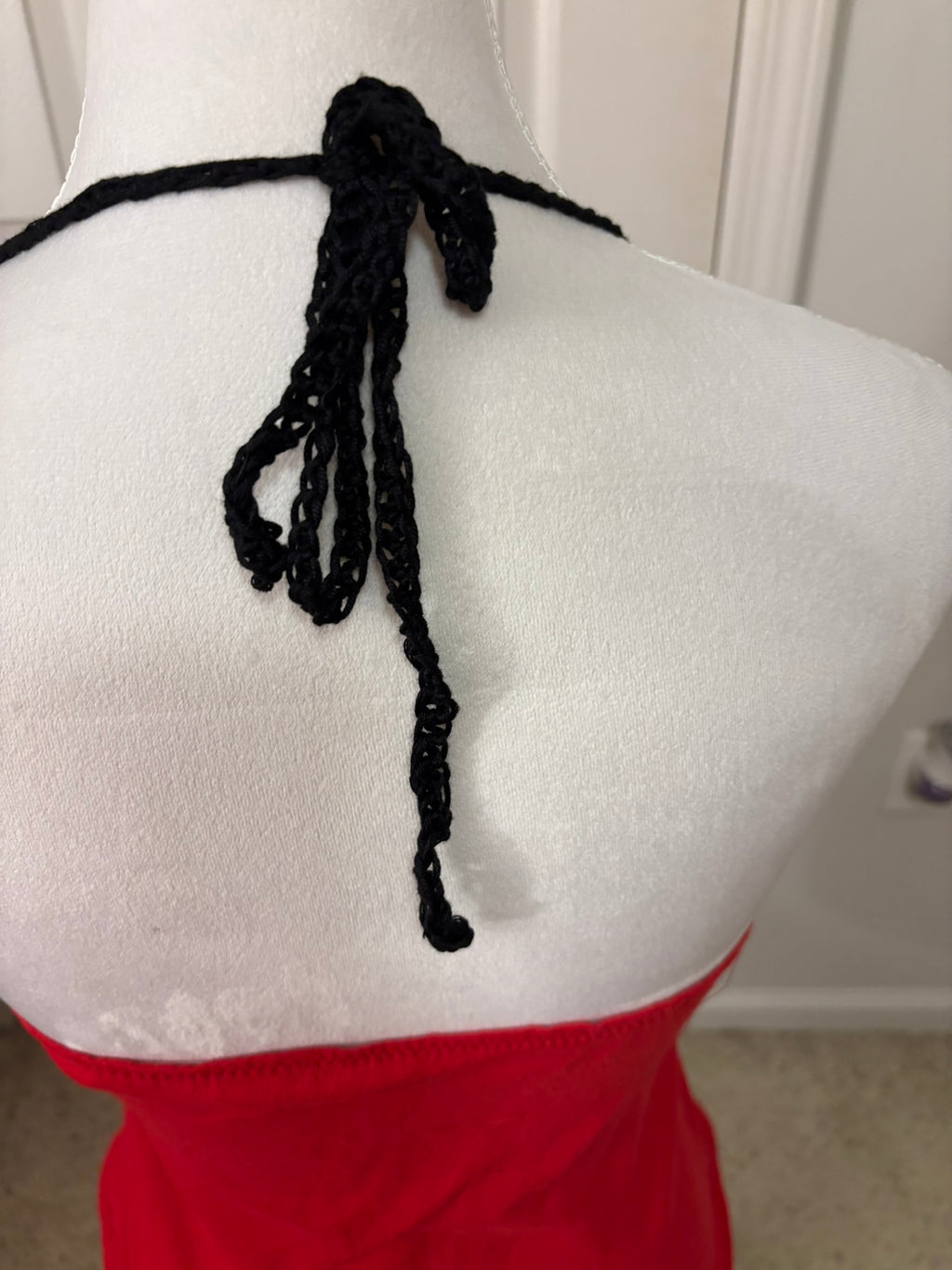 Close-up back view of a red UGA halter top with black crocheted tie detail at the neckline.
