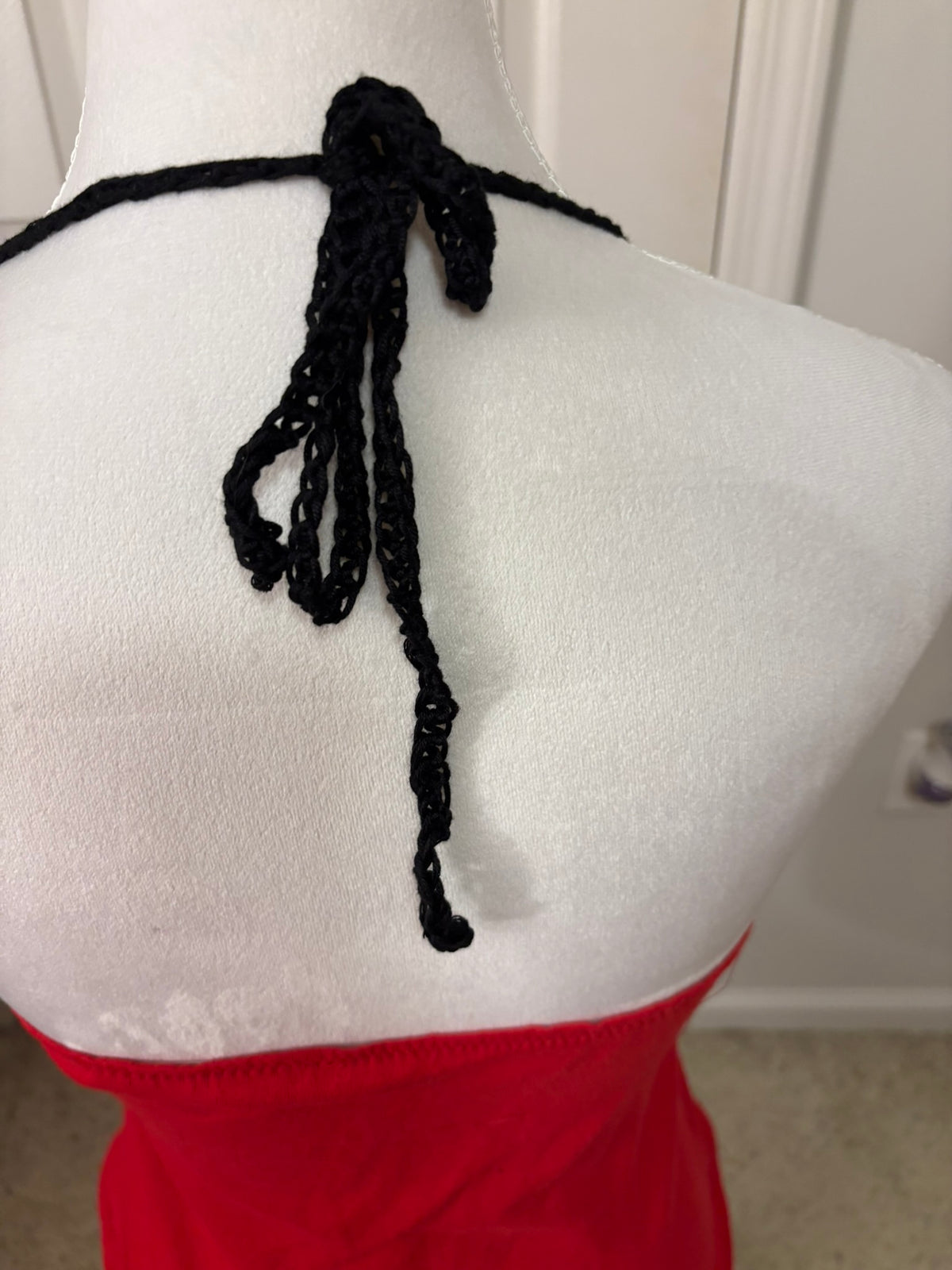 Close-up back view of a red UGA halter top with black crocheted tie detail at the neckline.