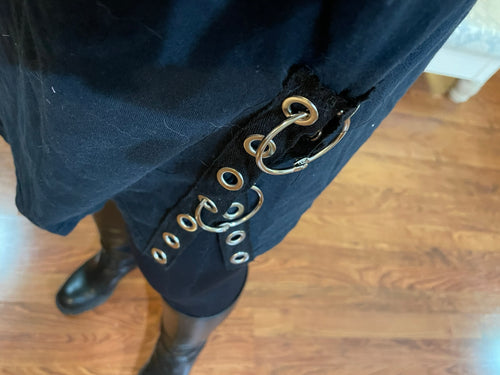 Close-up of a black grommet and silver rings details along bottom hem.